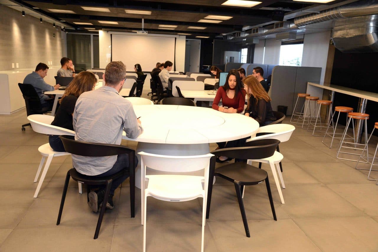 Espaço aberto do Varejo Inteligente com mesas redondas e tela ao fundo